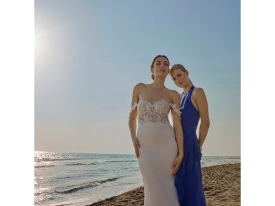 Damigella di spalle che indossa un vestito da cerimonia beige con scollo a V sulla schiena. 