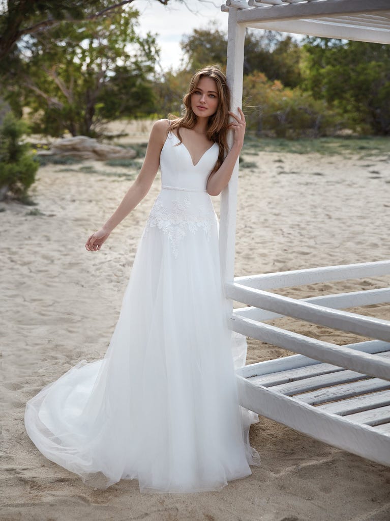 Mermaid dress of embroidered champagne tulle with plunging V-neck in front and back and short sleeves. The tulle overskirt adds volume and romanticism.