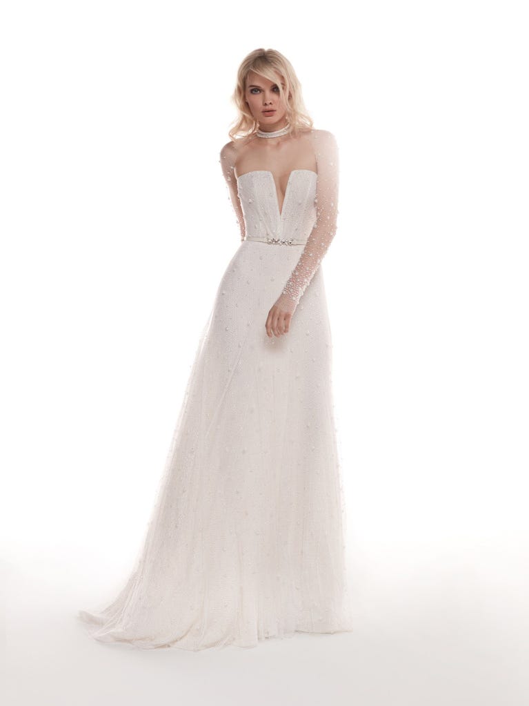 Romantic mermaid wedding dress of light pink Chantilly lace with plunging V-neck that continues on the sleeves. The keyhole opening in back and the tulle overskirt add romanticism to this dreamy dress.