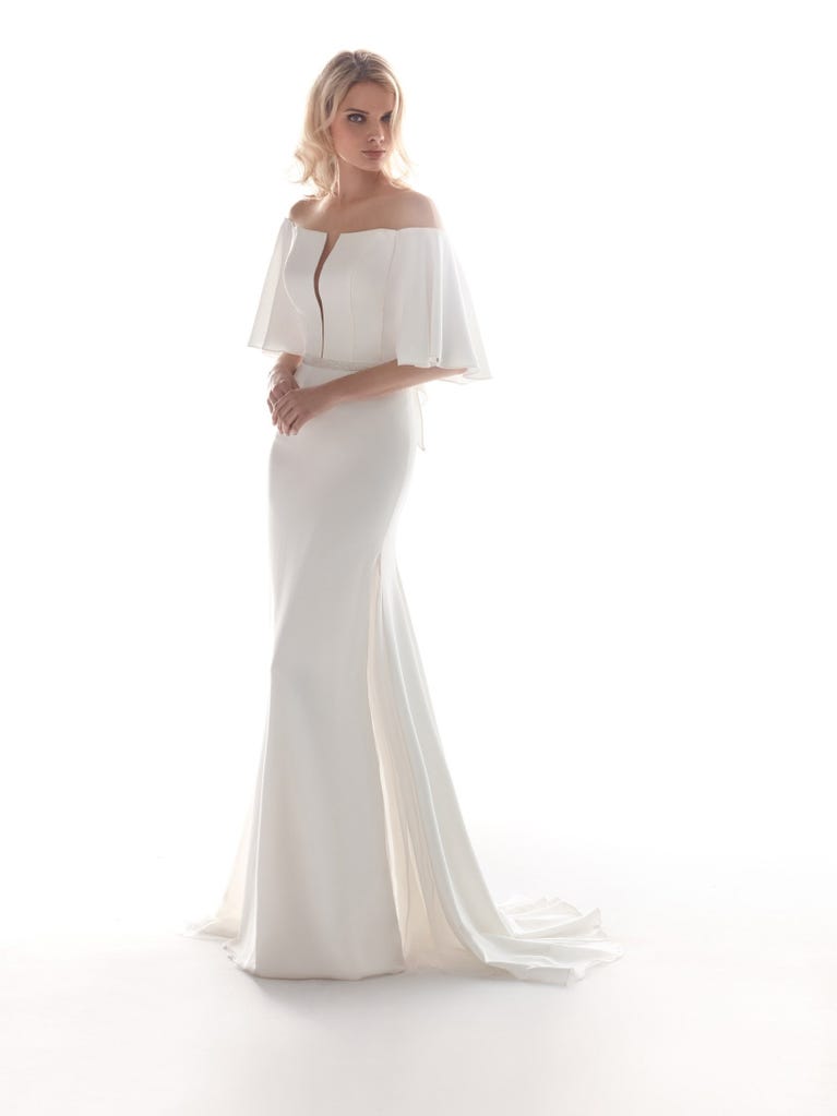 Romantic mermaid wedding dress of light pink Chantilly lace with plunging V-neck that continues on the sleeves. The keyhole opening in back and the tulle overskirt add romanticism to this dreamy dress.
