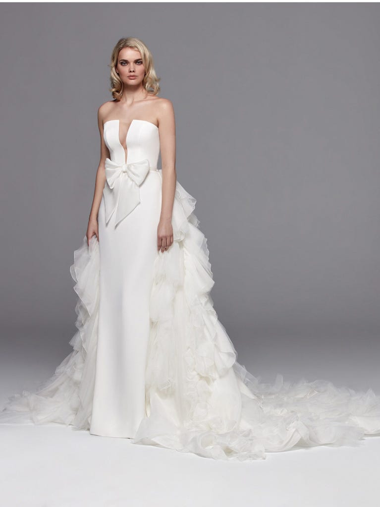 Romantic mermaid wedding dress of light pink Chantilly lace with plunging V-neck that continues on the sleeves. The keyhole opening in back and the tulle overskirt add romanticism to this dreamy dress.