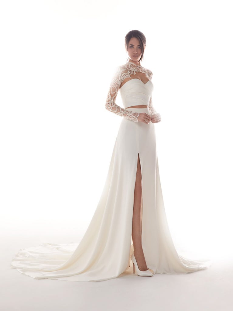 Romantic mermaid wedding dress of light pink Chantilly lace with plunging V-neck that continues on the sleeves. The keyhole opening in back and the tulle overskirt add romanticism to this dreamy dress.