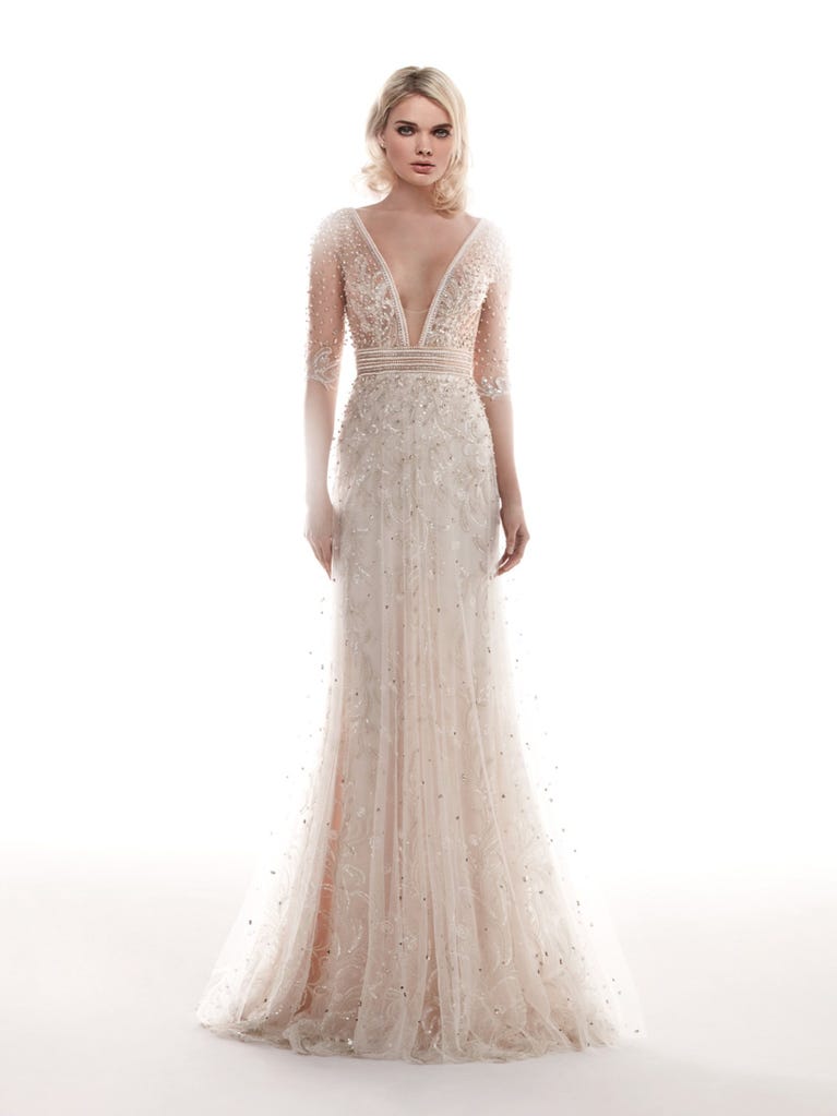 Romantic mermaid wedding dress of light pink Chantilly lace with plunging V-neck that continues on the sleeves. The keyhole opening in back and the tulle overskirt add romanticism to this dreamy dress.