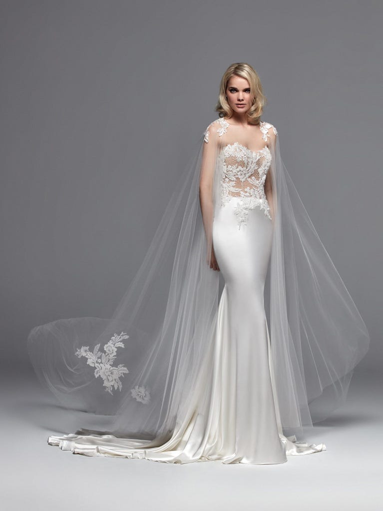 Romantic mermaid wedding dress of light pink Chantilly lace with plunging V-neck that continues on the sleeves. The keyhole opening in back and the tulle overskirt add romanticism to this dreamy dress.