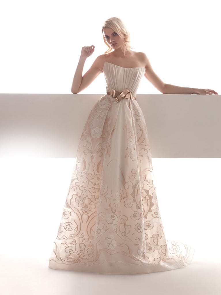 Romantic mermaid wedding dress of light pink Chantilly lace with plunging V-neck that continues on the sleeves. The keyhole opening in back and the tulle overskirt add romanticism to this dreamy dress.