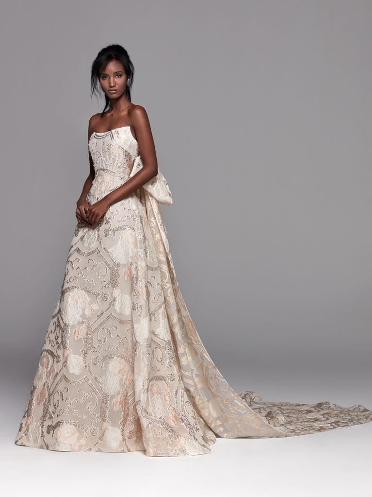Romantic mermaid wedding dress of light pink Chantilly lace with plunging V-neck that continues on the sleeves. The keyhole opening in back and the tulle overskirt add romanticism to this dreamy dress.