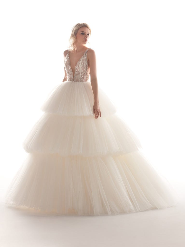 Romantic mermaid wedding dress of light pink Chantilly lace with plunging V-neck that continues on the sleeves. The keyhole opening in back and the tulle overskirt add romanticism to this dreamy dress.