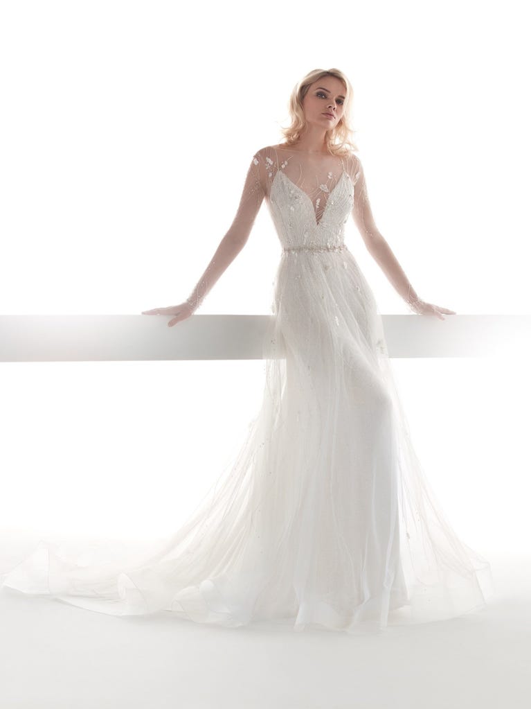 Romantic mermaid wedding dress of light pink Chantilly lace with plunging V-neck that continues on the sleeves. The keyhole opening in back and the tulle overskirt add romanticism to this dreamy dress.