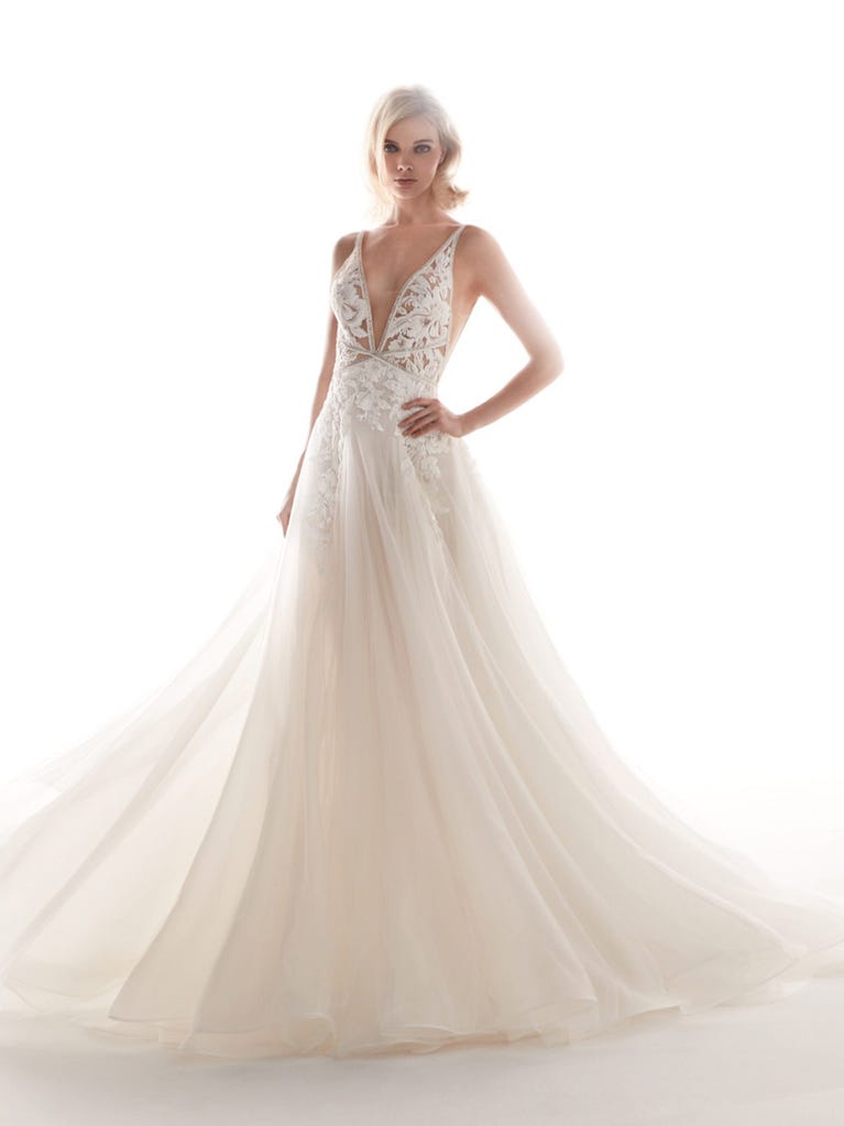 Romantic mermaid wedding dress of light pink Chantilly lace with plunging V-neck that continues on the sleeves. The keyhole opening in back and the tulle overskirt add romanticism to this dreamy dress.