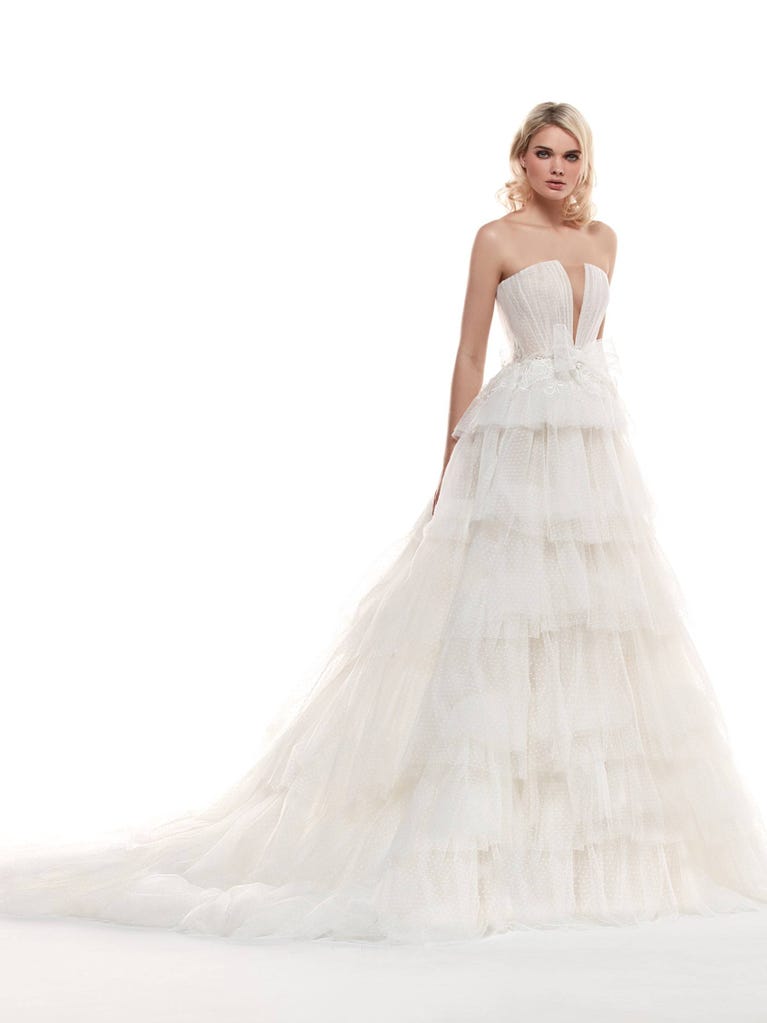 Romantic mermaid wedding dress of light pink Chantilly lace with plunging V-neck that continues on the sleeves. The keyhole opening in back and the tulle overskirt add romanticism to this dreamy dress.