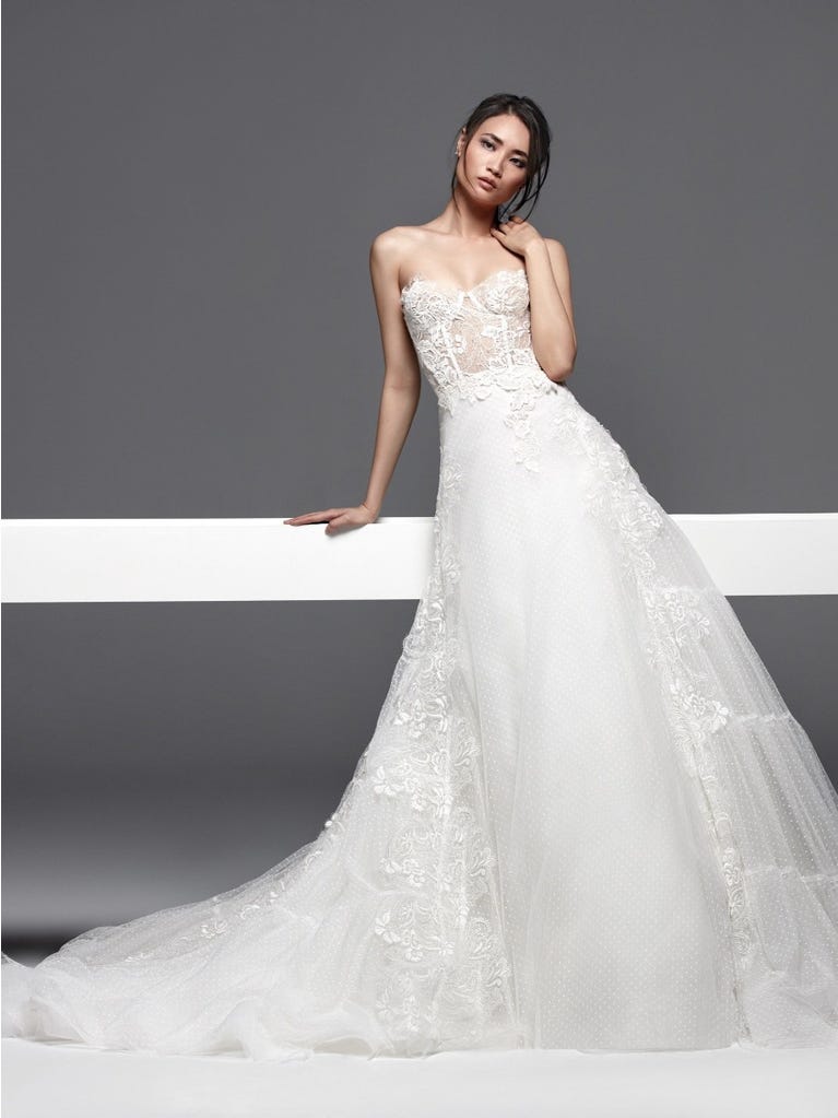 Romantic mermaid wedding dress of light pink Chantilly lace with plunging V-neck that continues on the sleeves. The keyhole opening in back and the tulle overskirt add romanticism to this dreamy dress.