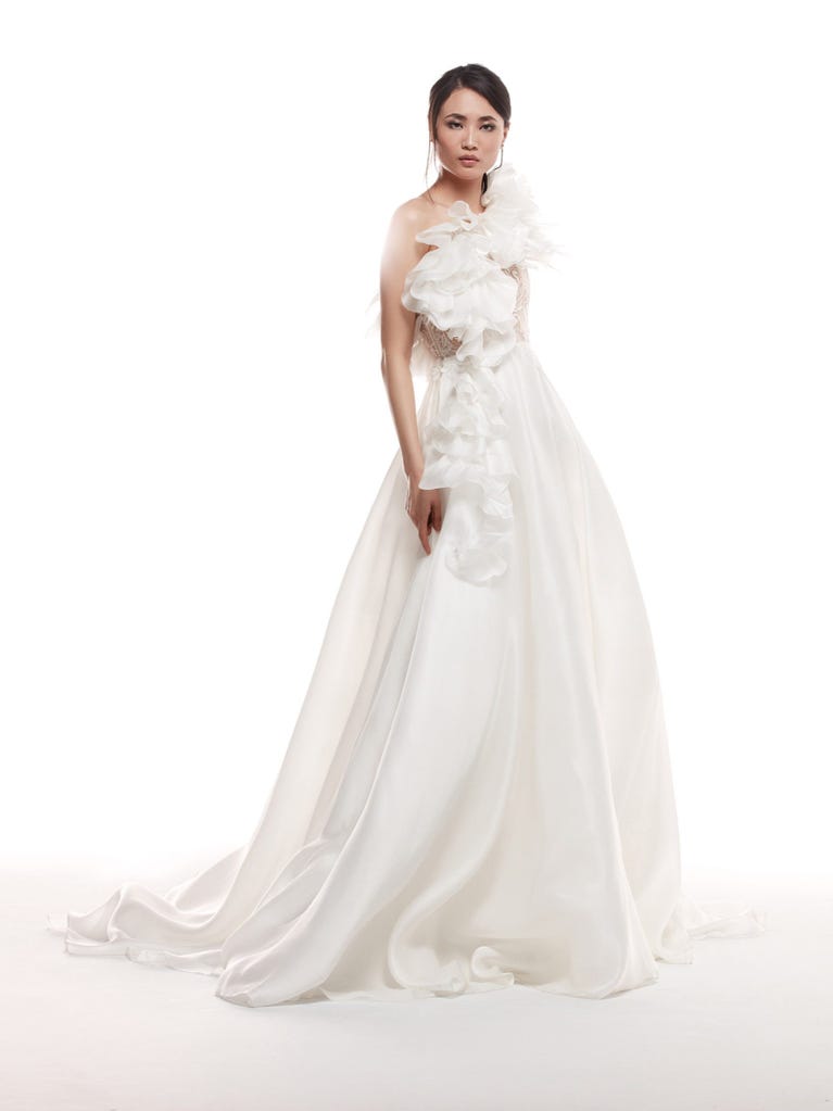 Romantic mermaid wedding dress of light pink Chantilly lace with plunging V-neck that continues on the sleeves. The keyhole opening in back and the tulle overskirt add romanticism to this dreamy dress.