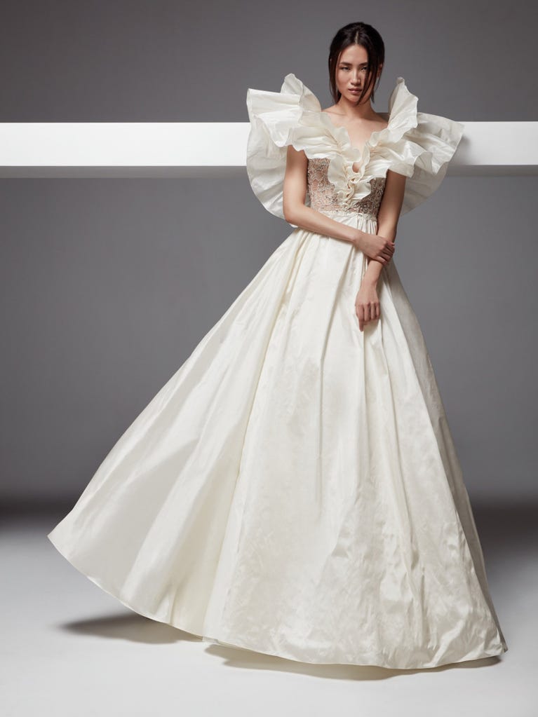 Romantic mermaid wedding dress of light pink Chantilly lace with plunging V-neck that continues on the sleeves. The keyhole opening in back and the tulle overskirt add romanticism to this dreamy dress.