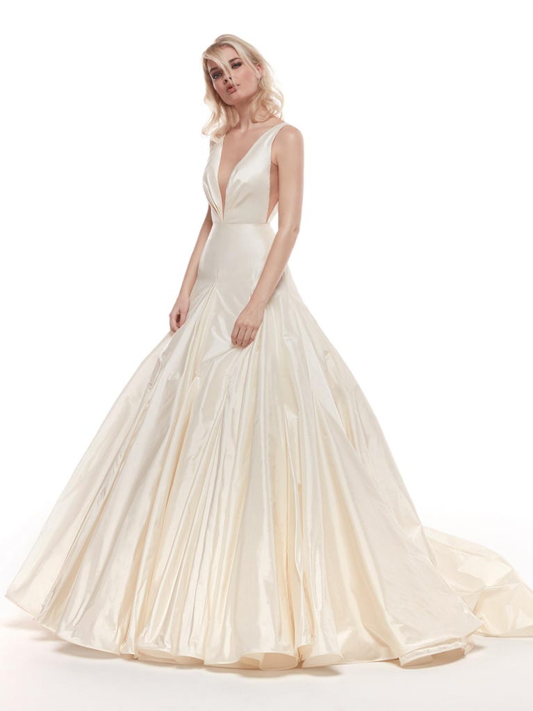 Romantic mermaid wedding dress of light pink Chantilly lace with plunging V-neck that continues on the sleeves. The keyhole opening in back and the tulle overskirt add romanticism to this dreamy dress.