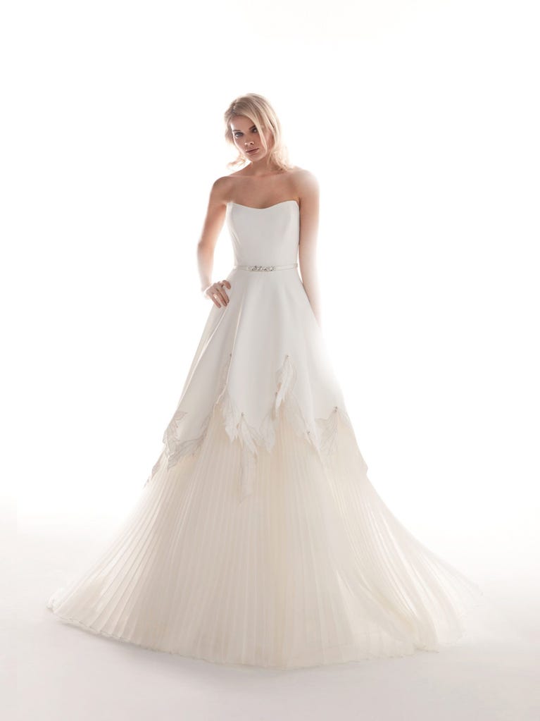 Romantic mermaid wedding dress of light pink Chantilly lace with plunging V-neck that continues on the sleeves. The keyhole opening in back and the tulle overskirt add romanticism to this dreamy dress.