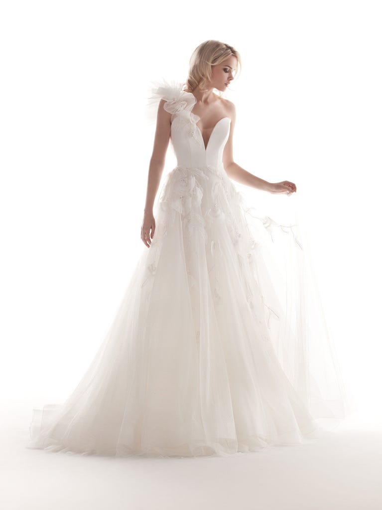 Romantic mermaid wedding dress of light pink Chantilly lace with plunging V-neck that continues on the sleeves. The keyhole opening in back and the tulle overskirt add romanticism to this dreamy dress.