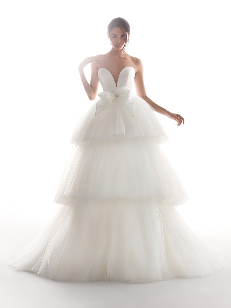 Romantic mermaid wedding dress of light pink Chantilly lace with plunging V-neck that continues on the sleeves. The keyhole opening in back and the tulle overskirt add romanticism to this dreamy dress.