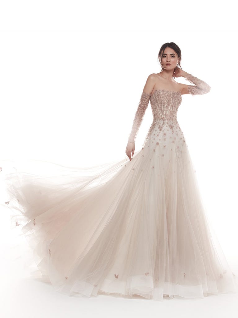 Romantic mermaid wedding dress of light pink Chantilly lace with plunging V-neck that continues on the sleeves. The keyhole opening in back and the tulle overskirt add romanticism to this dreamy dress.