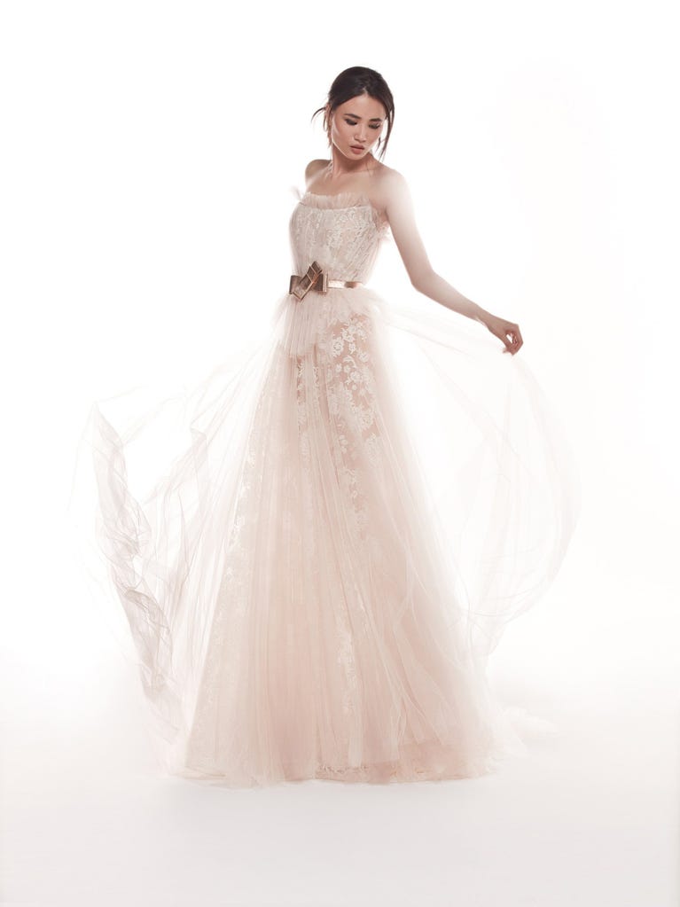 Romantic mermaid wedding dress of light pink Chantilly lace with plunging V-neck that continues on the sleeves. The keyhole opening in back and the tulle overskirt add romanticism to this dreamy dress.