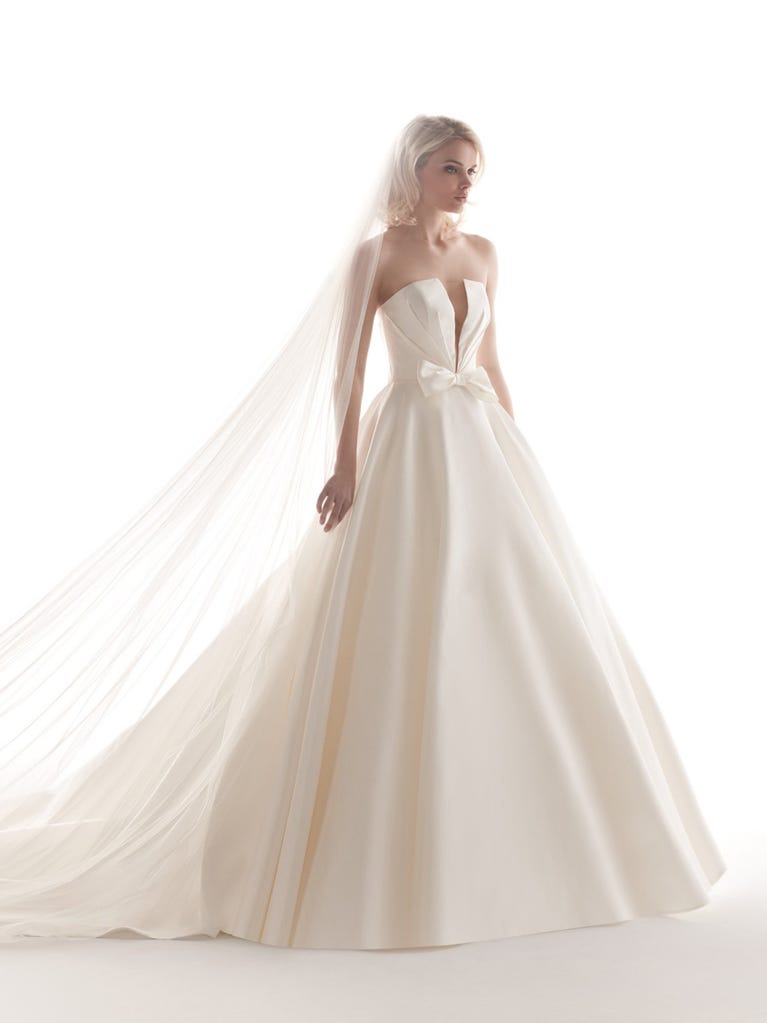 Romantic mermaid wedding dress of light pink Chantilly lace with plunging V-neck that continues on the sleeves. The keyhole opening in back and the tulle overskirt add romanticism to this dreamy dress.