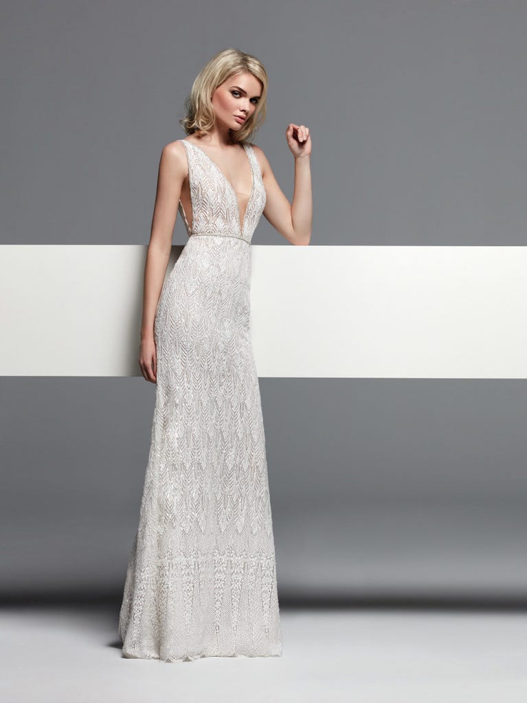 Romantic mermaid wedding dress of light pink Chantilly lace with plunging V-neck that continues on the sleeves. The keyhole opening in back and the tulle overskirt add romanticism to this dreamy dress.