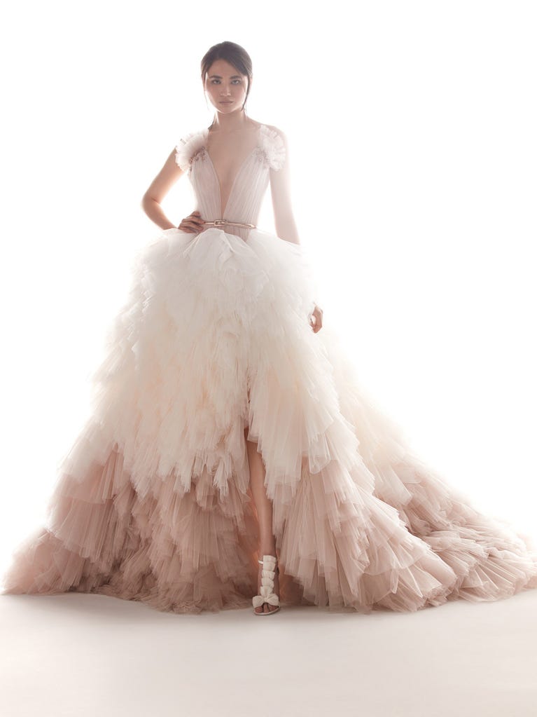 Romantic mermaid wedding dress of light pink Chantilly lace with plunging V-neck that continues on the sleeves. The keyhole opening in back and the tulle overskirt add romanticism to this dreamy dress.