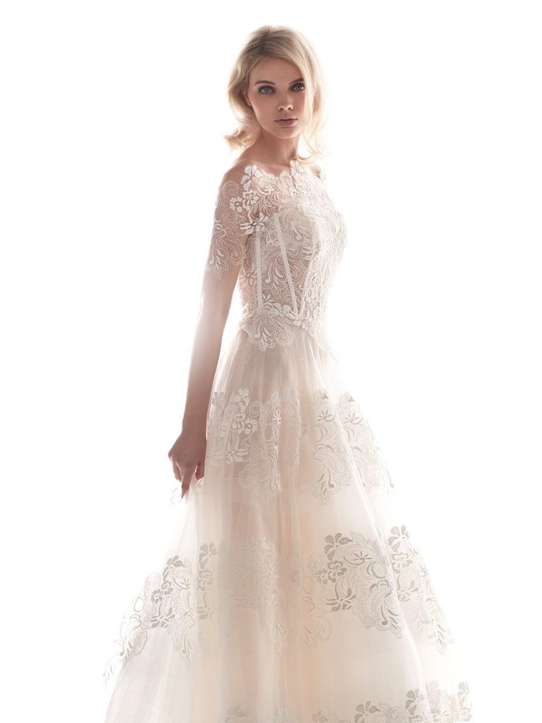 Romantic mermaid wedding dress of light pink Chantilly lace with plunging V-neck that continues on the sleeves. The keyhole opening in back and the tulle overskirt add romanticism to this dreamy dress.