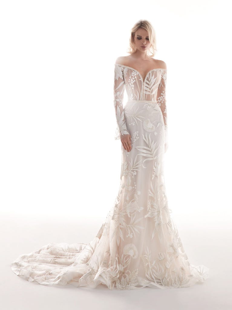 Romantic mermaid wedding dress of light pink Chantilly lace with plunging V-neck that continues on the sleeves. The keyhole opening in back and the tulle overskirt add romanticism to this dreamy dress.