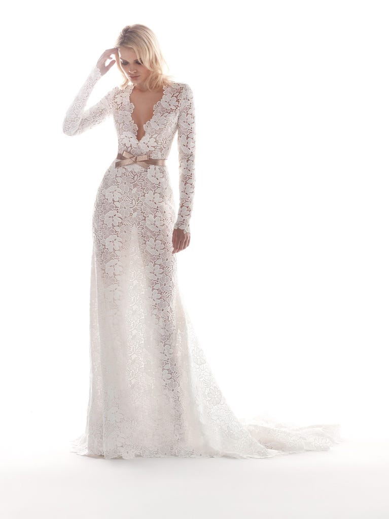 Romantic mermaid wedding dress of light pink Chantilly lace with plunging V-neck that continues on the sleeves. The keyhole opening in back and the tulle overskirt add romanticism to this dreamy dress.