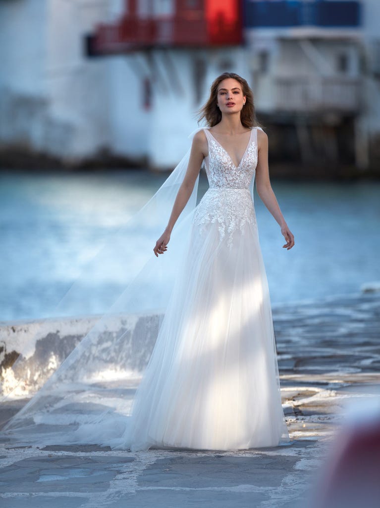 Mermaid dress of embroidered champagne tulle with plunging V-neck in front and back and short sleeves. The tulle overskirt adds volume and romanticism.
