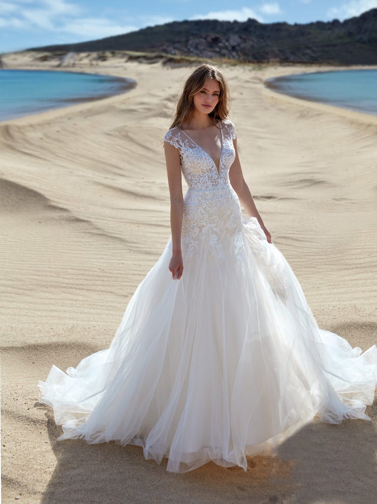 Mermaid dress of embroidered champagne tulle with plunging V-neck in front and back and short sleeves. The tulle overskirt adds volume and romanticism.