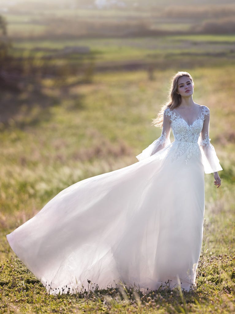 Mermaid dress of embroidered champagne tulle with plunging V-neck in front and back and short sleeves. The tulle overskirt adds volume and romanticism.