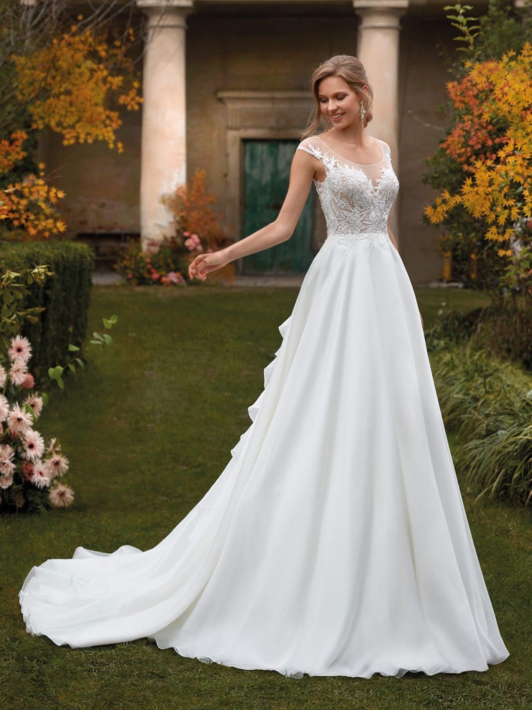 Mermaid dress of embroidered champagne tulle with plunging V-neck in front and back and short sleeves. The tulle overskirt adds volume and romanticism.