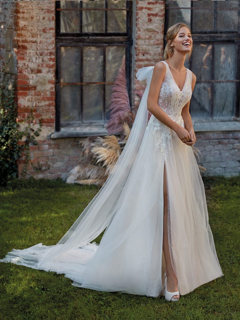 Mermaid dress of embroidered champagne tulle with plunging V-neck in front and back and short sleeves. The tulle overskirt adds volume and romanticism.