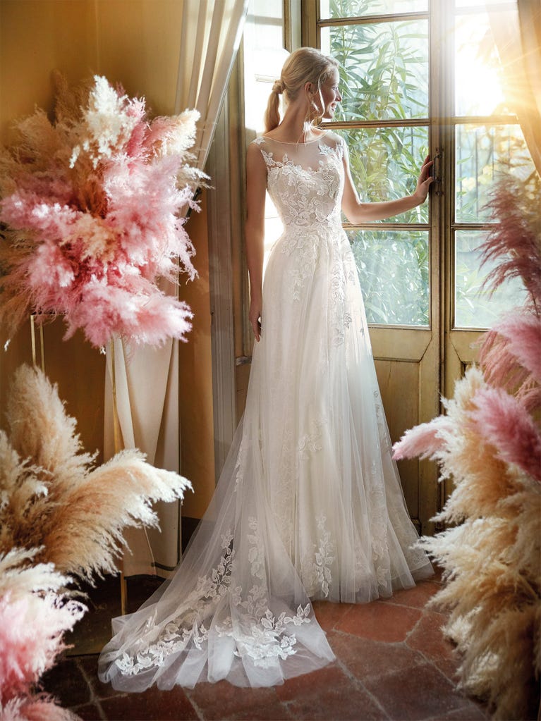 Mermaid dress of embroidered champagne tulle with plunging V-neck in front and back and short sleeves. The tulle overskirt adds volume and romanticism.