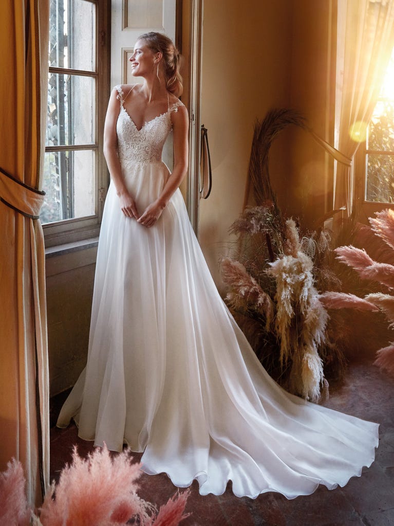 Mermaid dress of embroidered champagne tulle with plunging V-neck in front and back and short sleeves. The tulle overskirt adds volume and romanticism.
