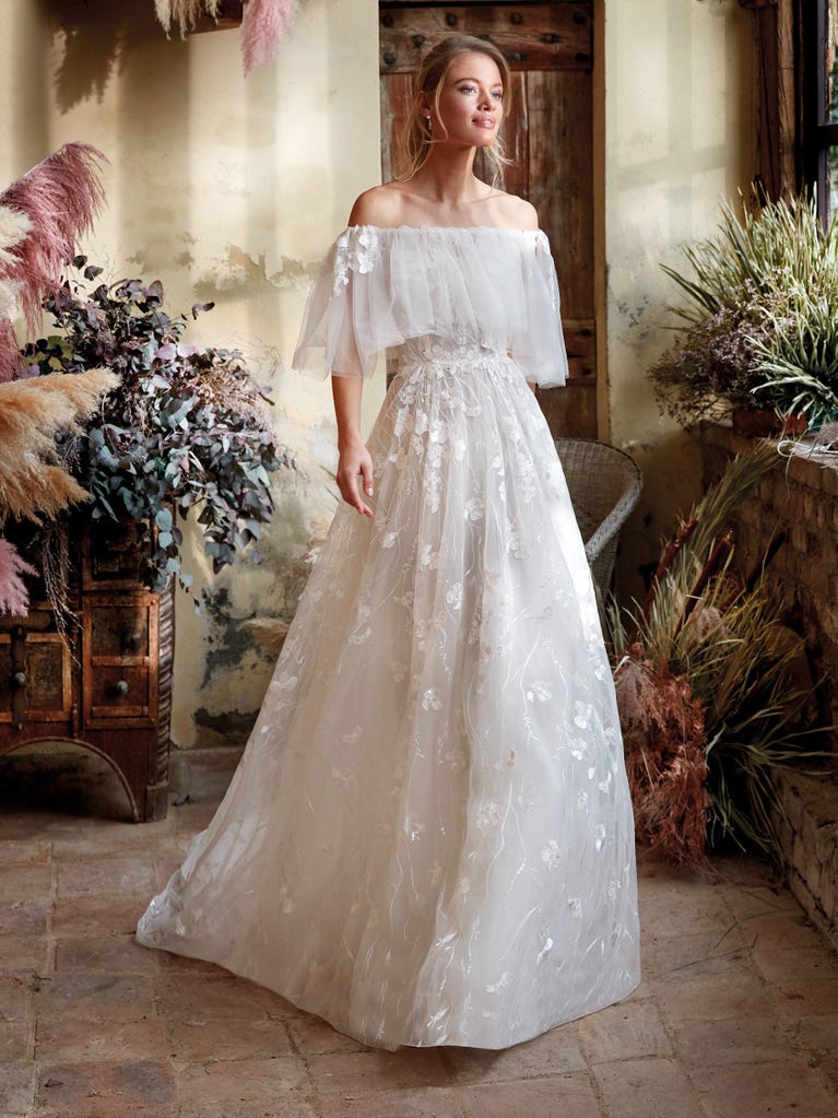 Mermaid dress of embroidered champagne tulle with plunging V-neck in front and back and short sleeves. The tulle overskirt adds volume and romanticism.