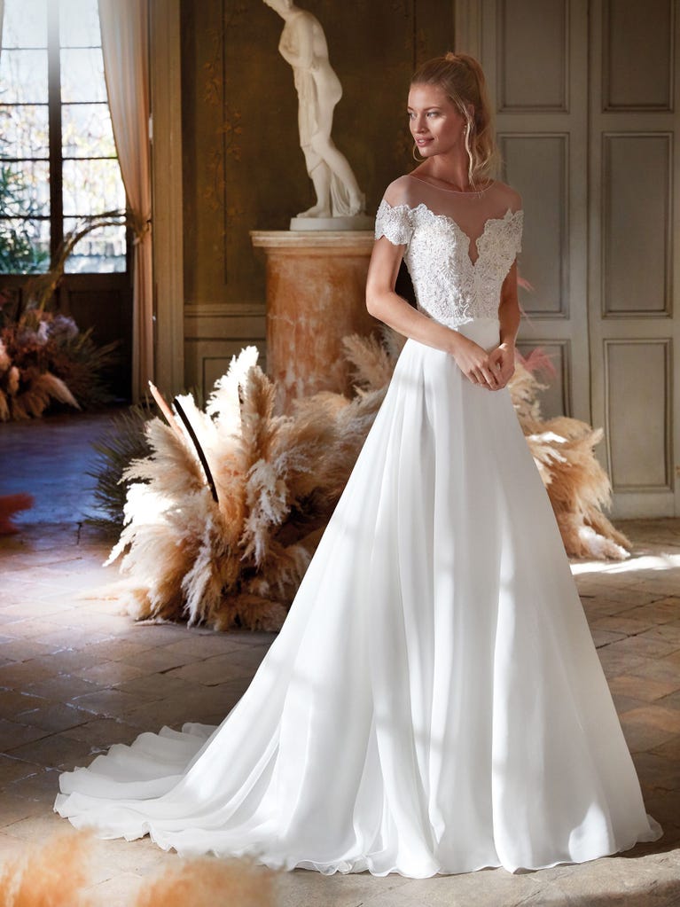 Mermaid dress of embroidered champagne tulle with plunging V-neck in front and back and short sleeves. The tulle overskirt adds volume and romanticism.