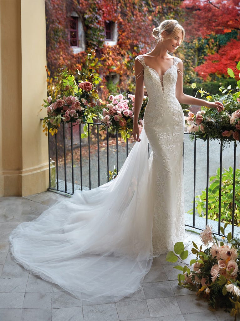 Flared wedding dress with crepe skirt and a tulle cape embroidered with silver beads. The three-dimensional flowers and minimalist, geometric superimpositions of fabrics create a contemporary, unique look for brides who want to surprise.