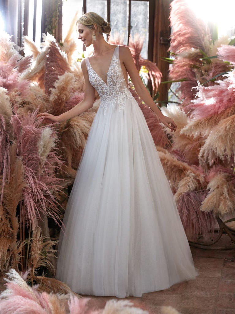Mermaid dress of embroidered champagne tulle with plunging V-neck in front and back and short sleeves. The tulle overskirt adds volume and romanticism.