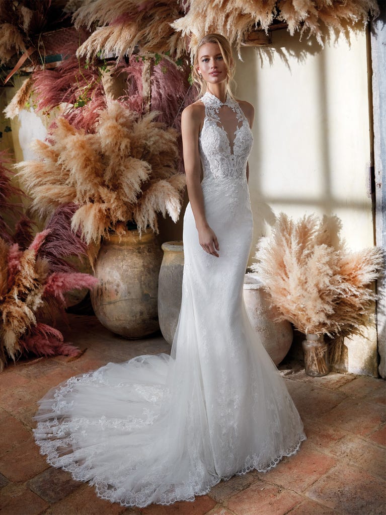 Flared wedding dress with crepe skirt and a tulle cape embroidered with silver beads. The three-dimensional flowers and minimalist, geometric superimpositions of fabrics create a contemporary, unique look for brides who want to surprise.