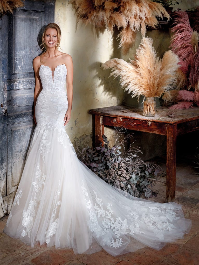 Flared wedding dress with crepe skirt and a tulle cape embroidered with silver beads. The three-dimensional flowers and minimalist, geometric superimpositions of fabrics create a contemporary, unique look for brides who want to surprise.