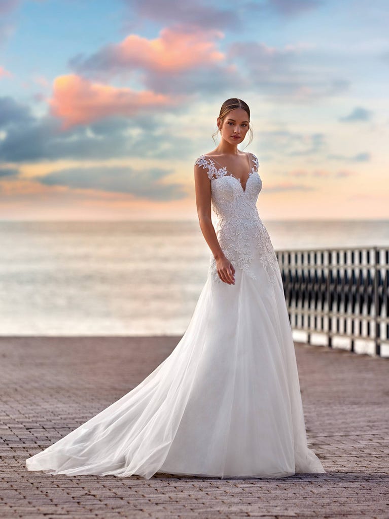 Flared wedding dress with voluminous yet lightweight tulle skirt with lace embroidered with floral motifs. For brides who dream of a romantic, feminine dress to say “I do.”