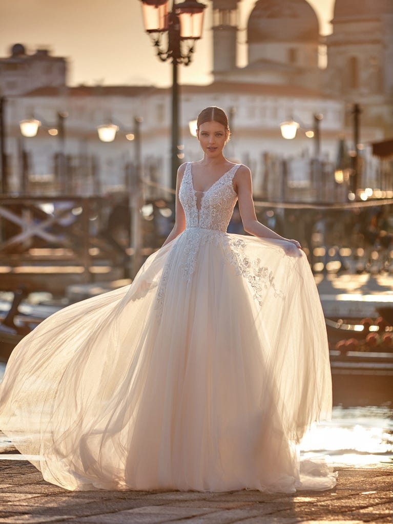 Flared wedding dress with voluminous yet lightweight tulle skirt with lace embroidered with floral motifs. For brides who dream of a romantic, feminine dress to say “I do.”