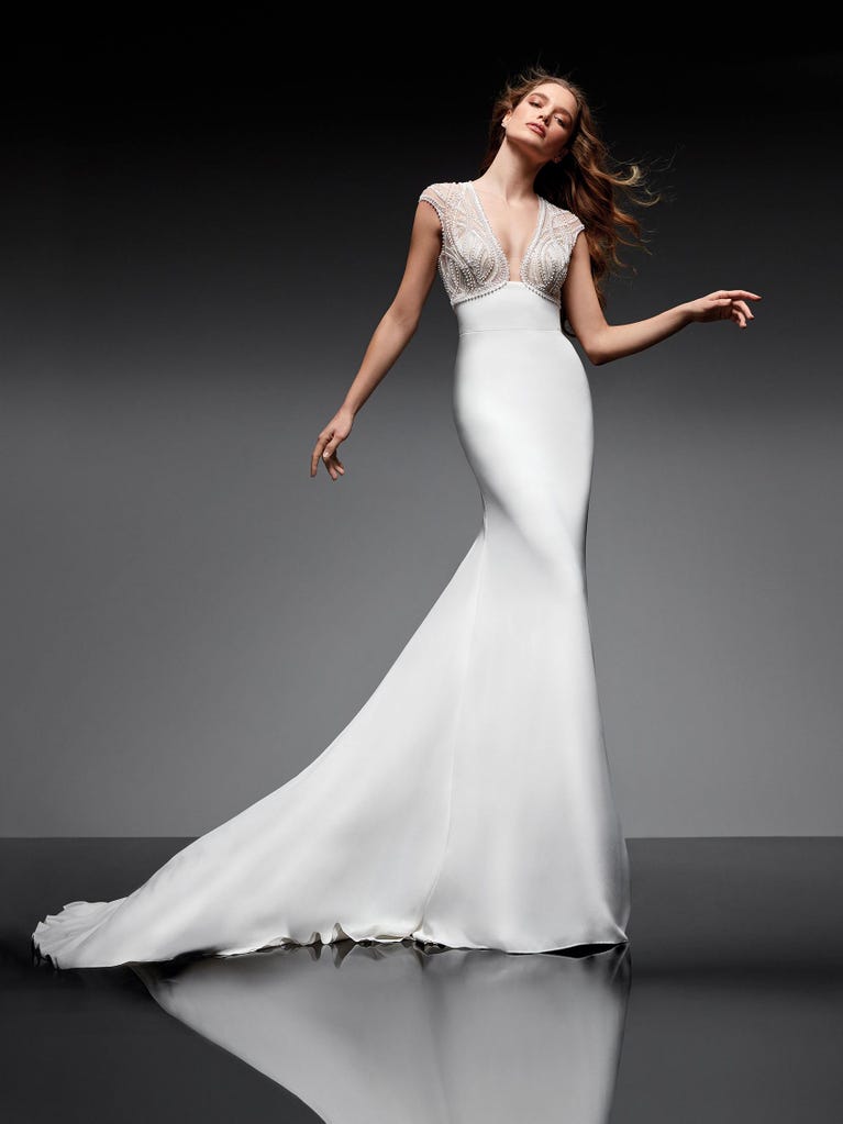 Beautiful A-line wedding dress in champagne tulle with embroidered beading and elegant 3D flowers. The straps expose the back with an elegant neckline.