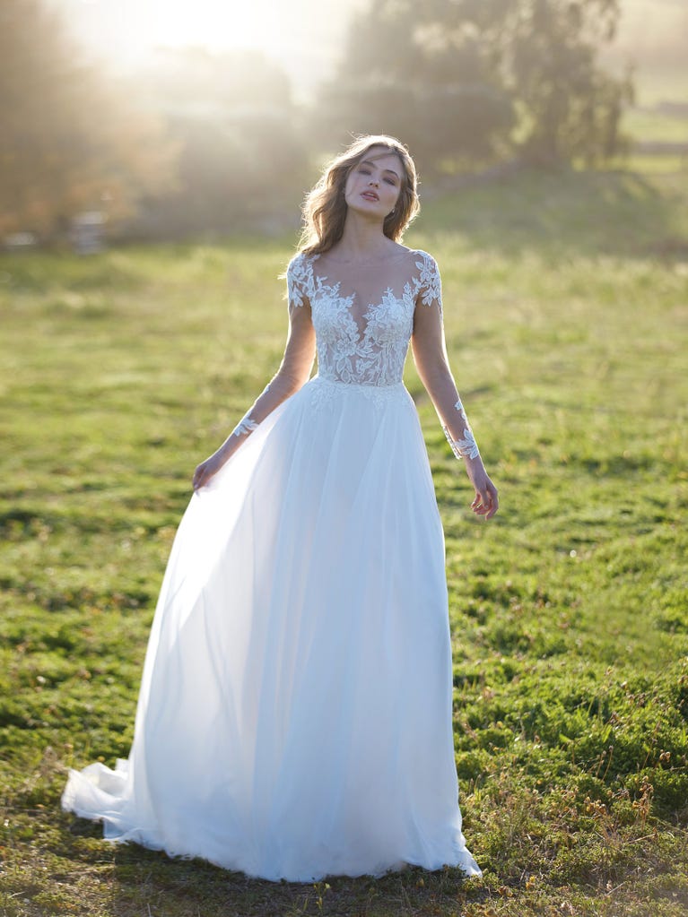 Mermaid dress of embroidered champagne tulle with plunging V-neck in front and back and short sleeves. The tulle overskirt adds volume and romanticism.