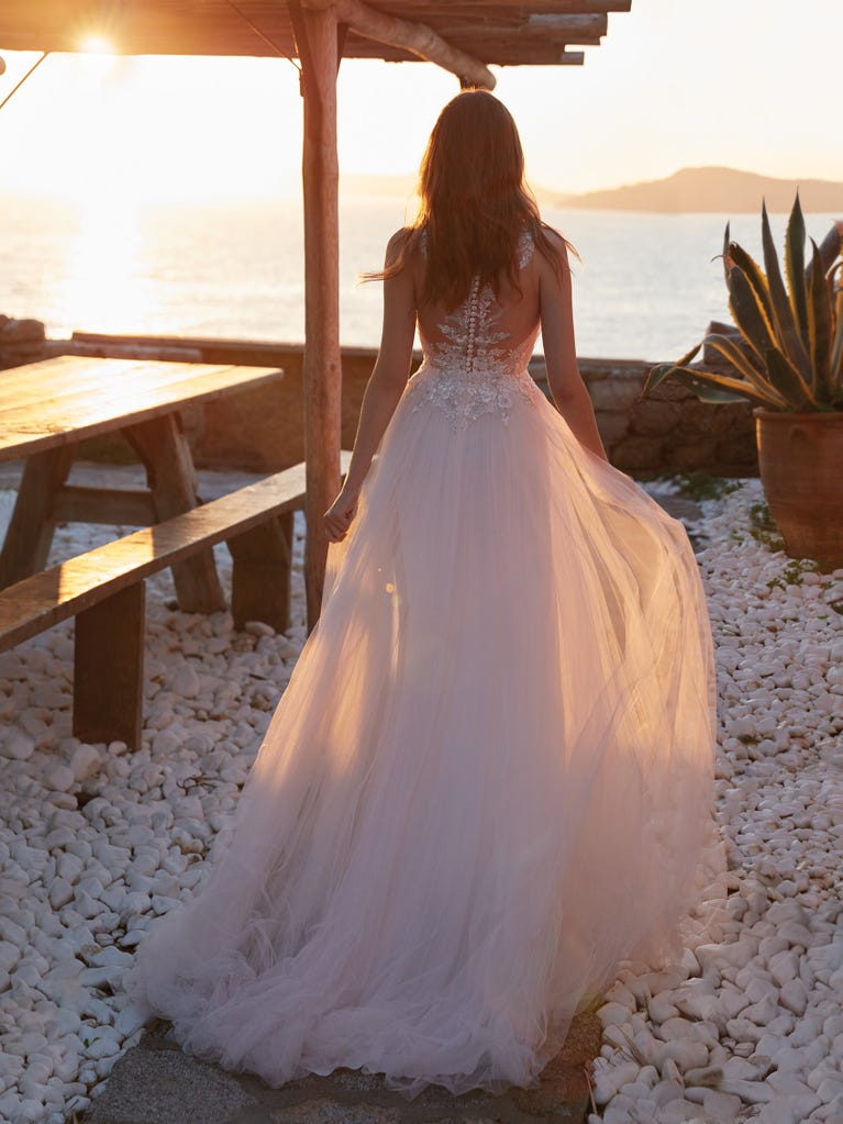 Mermaid dress of embroidered champagne tulle with plunging V-neck in front and back and short sleeves. The tulle overskirt adds volume and romanticism.