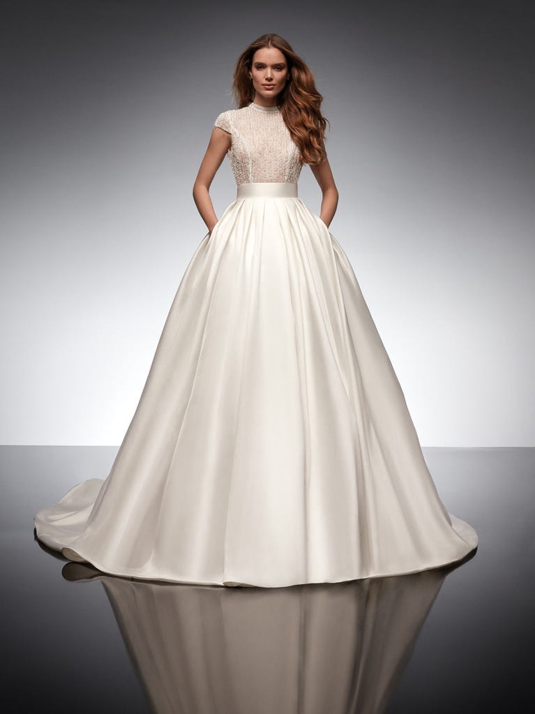 Beautiful A-line wedding dress in champagne tulle with embroidered beading and elegant 3D flowers. The straps expose the back with an elegant neckline.