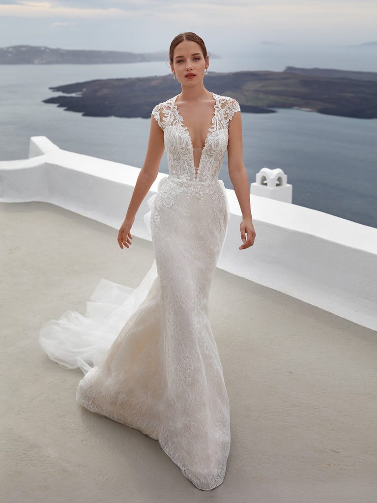 Flared wedding dress with crepe skirt and a tulle cape embroidered with silver beads. The three-dimensional flowers and minimalist, geometric superimpositions of fabrics create a contemporary, unique look for brides who want to surprise.