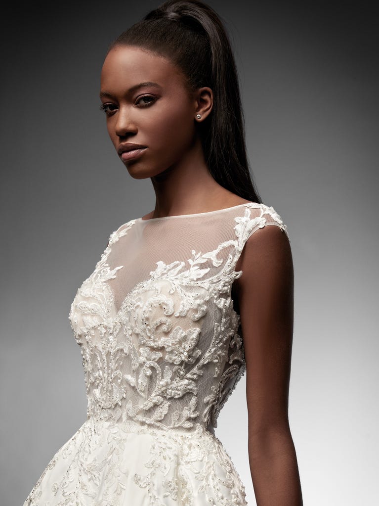 Beautiful A-line wedding dress in champagne tulle with embroidered beading and elegant 3D flowers. The straps expose the back with an elegant neckline.